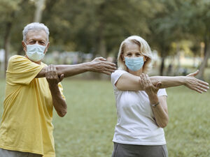 Two seniors outdoors exercising with face masks 2022